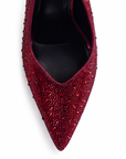 Vista del detalle en la punta fina con pedrería brillante de la zapatilla roja tipo stiletto para dama con tacón medio 10 cm