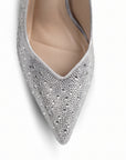 Vista del detalle en la punta fina con pedrería brillante de la zapatilla plateada tipo stiletto para dama con tacón medio 10 cm