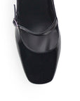vista del detalle en correa ajustable de las zapatillas negras de charol para dama destalonadas con tacón medio 8cm