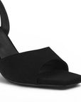 Vista a detalle de punta cuadrada de diseño descubierto en zapatilla negra para mujer con pulsera ajustable al tobillo