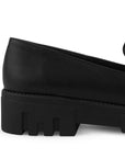 Vista trasera de la suela chunky tipo track del mocasín negro para dama con antifaz decorativo en el empeine