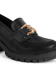 Detalle del material cabra sintético en el mocasín negro con punta redonda y herraje decorativo para dama