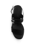 Vista superior de zapatilla negra de diseño descubierto para mujer con adorno de hebilla en tiras anchas y correa ajustable trasera