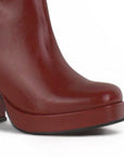Detalle del material sintético en la bota vino con herraje metálico, plataforma y tacón medio 9 cm para dama