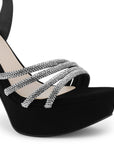 Vista a detalle de tiras con pedrería zapatilla negra para mujer con pulsera ajustable y tacón alto delgado de 13cm