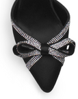 Vista de material shantung en zapatilla con punta fina, moño de pedrería y tacón de 7cm color negro