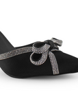 Vista a detalle de moño con pedrería y punta fina en zapatilla negra para mujer