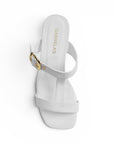 vista superior de zapatillas blancas con hebilla dorada en tiras gruesas para dama