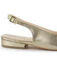 Vista trasera de flat dorados para mujer con diseño destalonado de piso y pulsera con hebilla ajustable