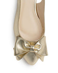 Vista de material sintético en flats dorados para mujer con moño en punta fina destalonado con pulsera ajustable trasera