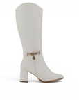 Vista lateral de bota beige para dama con cremallera, cadena decorativa y tacón medio 7 cm