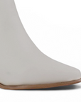Detalle del material sintético en la bota beige con punta fina, cadena metálica y tacón medio 7 cm para dama