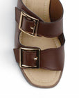 Vista de material sintético en zapatilla café para mujer con doble correa hebillas ajustables cuadradas y tacón grueso de 8cm