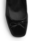 Vista de material charol en zapatilla negra destalonada para mujer con moño en punta cerrada y tacón bajo de 5cm