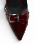 Vista del detalle en punta fina con detalles metálicos de la zapatilla vino de charol con tacón medio 7 cm para dama