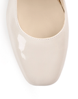 Vista de material charol en zapatilla beige para mujer con tacón bajo de 5cm