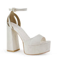 Vista diagonal de zapatilla para mujer con pulsera y tacón alto 13cm en color beige en acabado grabado