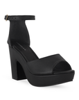 Vista diagonal de zapatilla para mujer con pulsera y tacón ancho en color negro cabra sintético