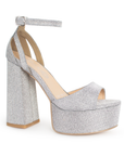 Vista diagonal de zapatilla para mujer con pulsera y tacón alto 13cm en color plata brilloso