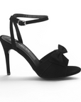 vista lateral de zapatillas negras con pulsera y tacon de mujer