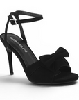 vista diagonal de zapatillas negras de mujer con pulsera y moño