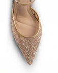 Vista del detalle en pedrería  de la zapatilla dorada tipo stiletto para dama con pulsera ajustable al tobillo y tacón medio 10cm