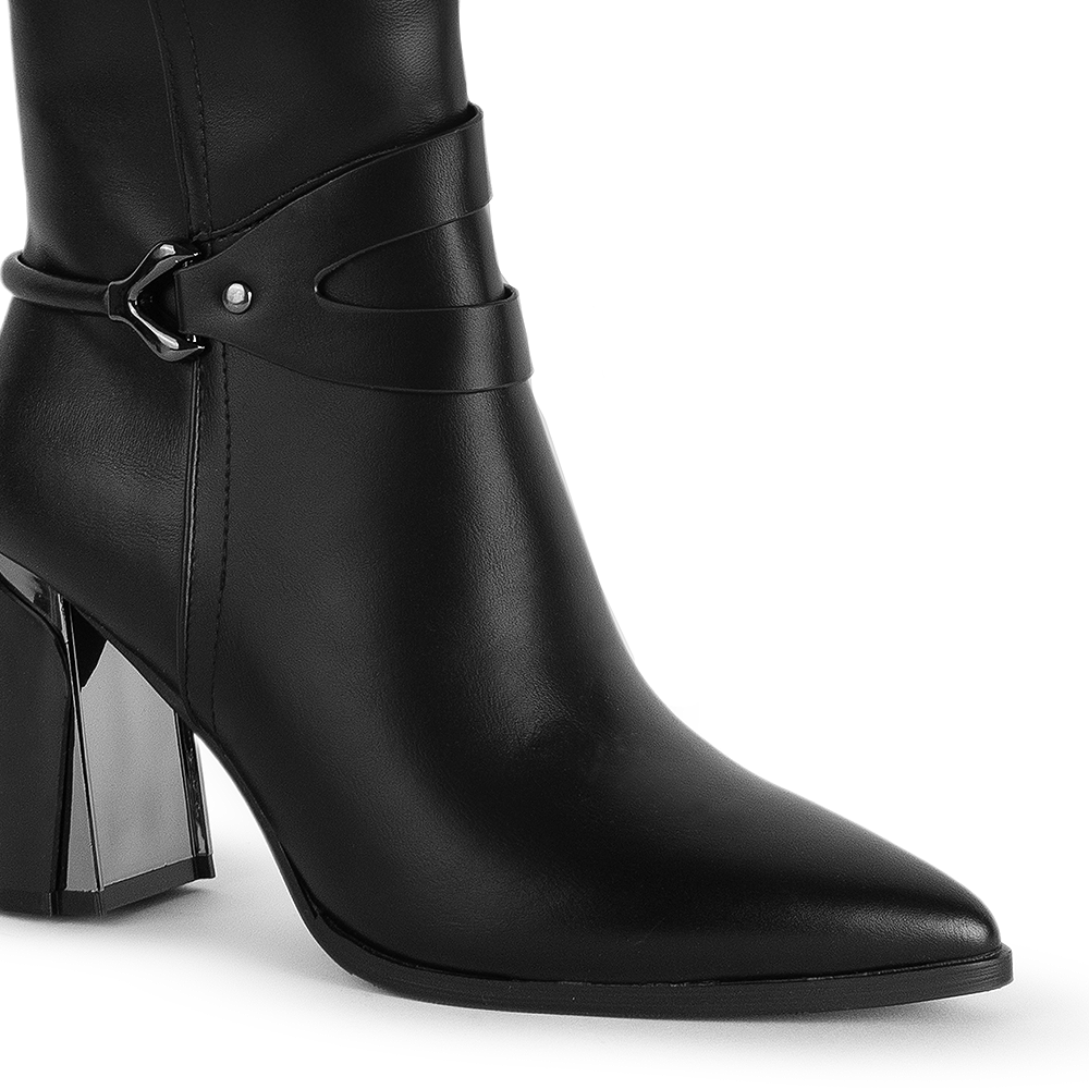 Detalle del material sintético en la bota negra con punta fina para dama con herraje decorativo y tacón medio 8cm 