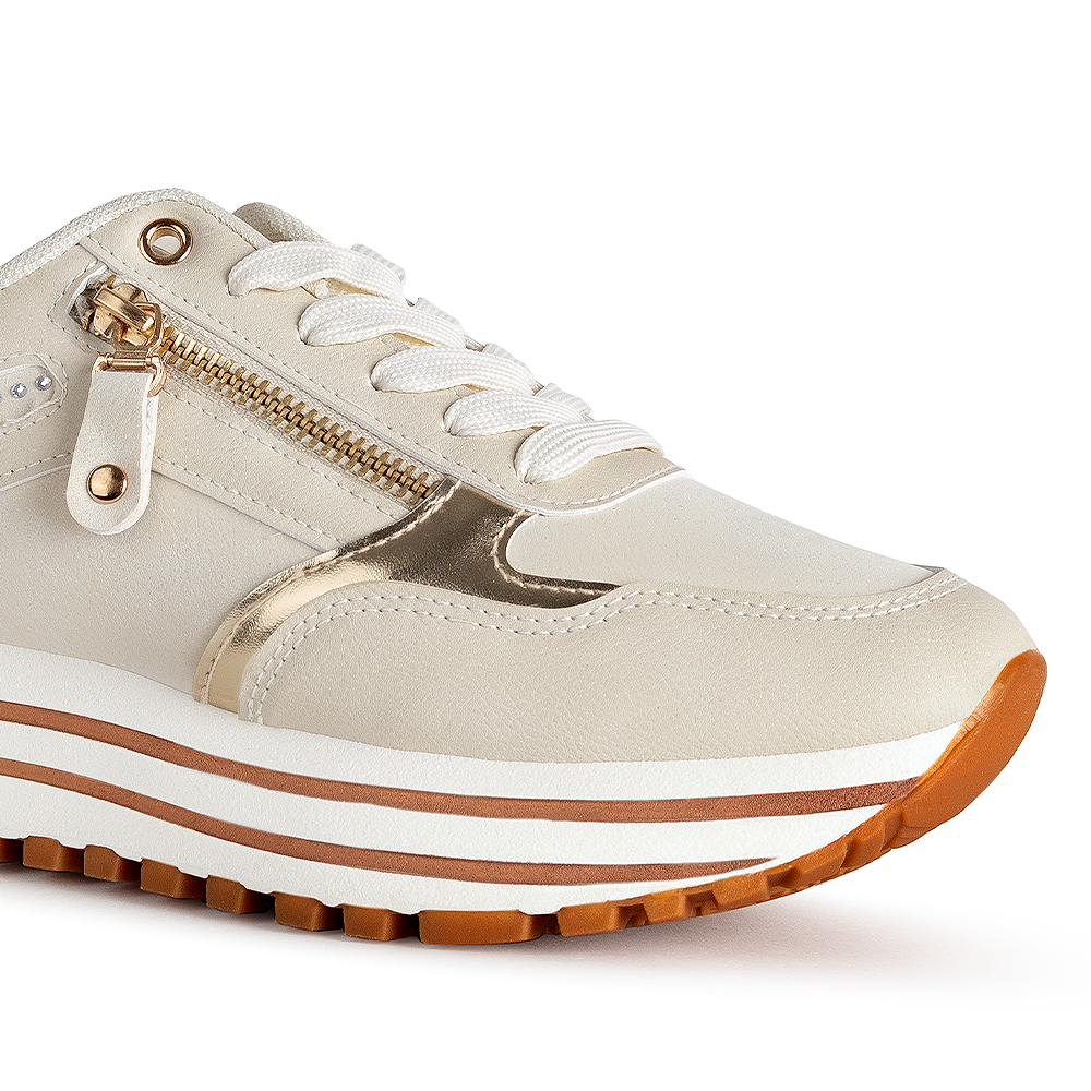 Detalle del material sintetico en tenis beige para dama con suela antiderrapante y detalles metalicos 
