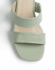 Vista de material charol en zapatilla beige para mujer con diseño abierto y doble tira ancha 