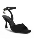 Vista diagonal de zapatilla negra de diseño descubierto para mujer con pulsera ajustable y tacón de 9cm