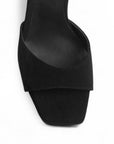 Vista de material buck en zapatilla negra para mujer de diseño descubierto con punta cuadrada pulsera ajustable al tobillo y tacón medio de 9cm