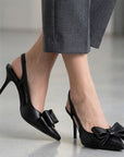 Zapatillas negras tipo stiletto destalonadas con moño al frente y tacón medio 8cm para dama 
