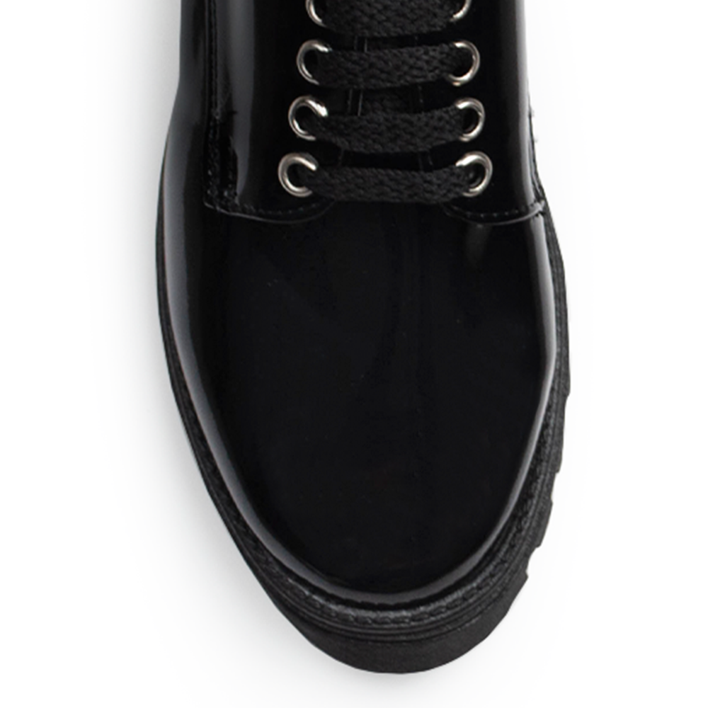 Vista de material charol en mocasín negro para mujer con agujetas, punta redonda y suela chunky tipo truck de tacón ancho bajo de 4cm