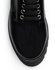 Vista de material charol en mocasín negro para mujer con agujetas, punta redonda y suela chunky tipo truck de tacón ancho bajo de 4cm