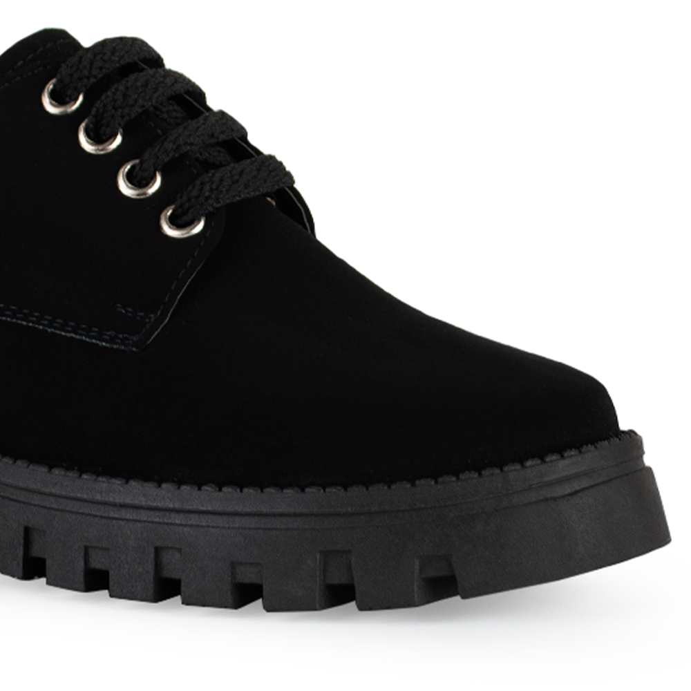Vista de punta en mocasín negro para mujer con suela chunky tipo truck, agujetas y tacón ancho bajo de 4cm