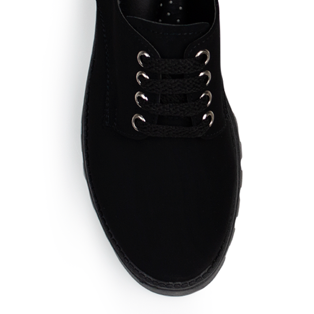 Vista de material buck en mocasín negro para mujer con agujetas, punta redonda y suela chunky tipo truck de tacón ancho bajo de 4cm