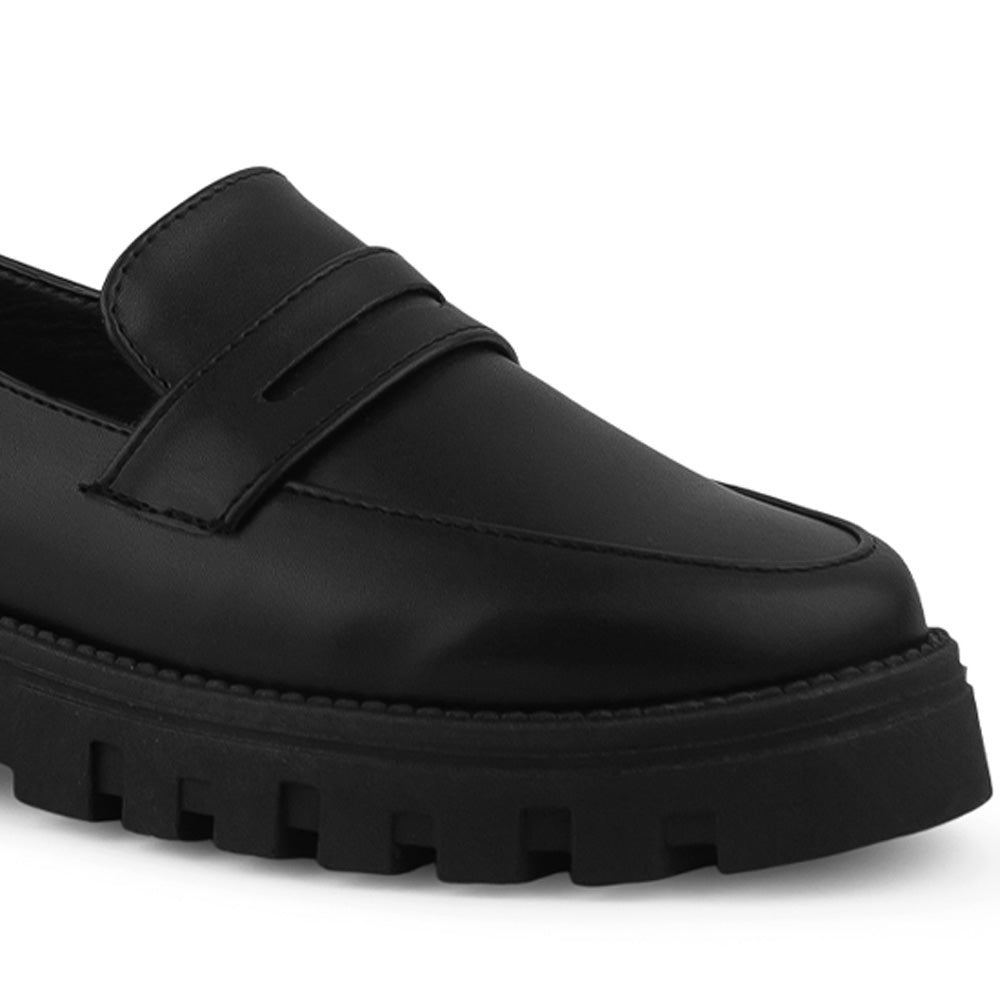 Detalle del material cabra sintético en el mocasín negro para dama con antifaz decorativo y suela chunky tipo track 