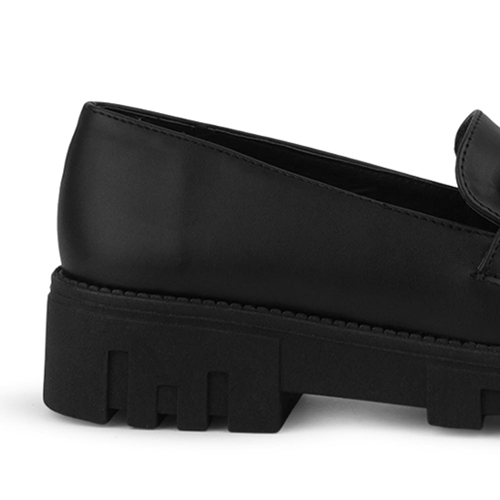 Vista trasera del tacón bajo tipo chunky en el mocasín negro para dama con herraje decorativo en el empeine 