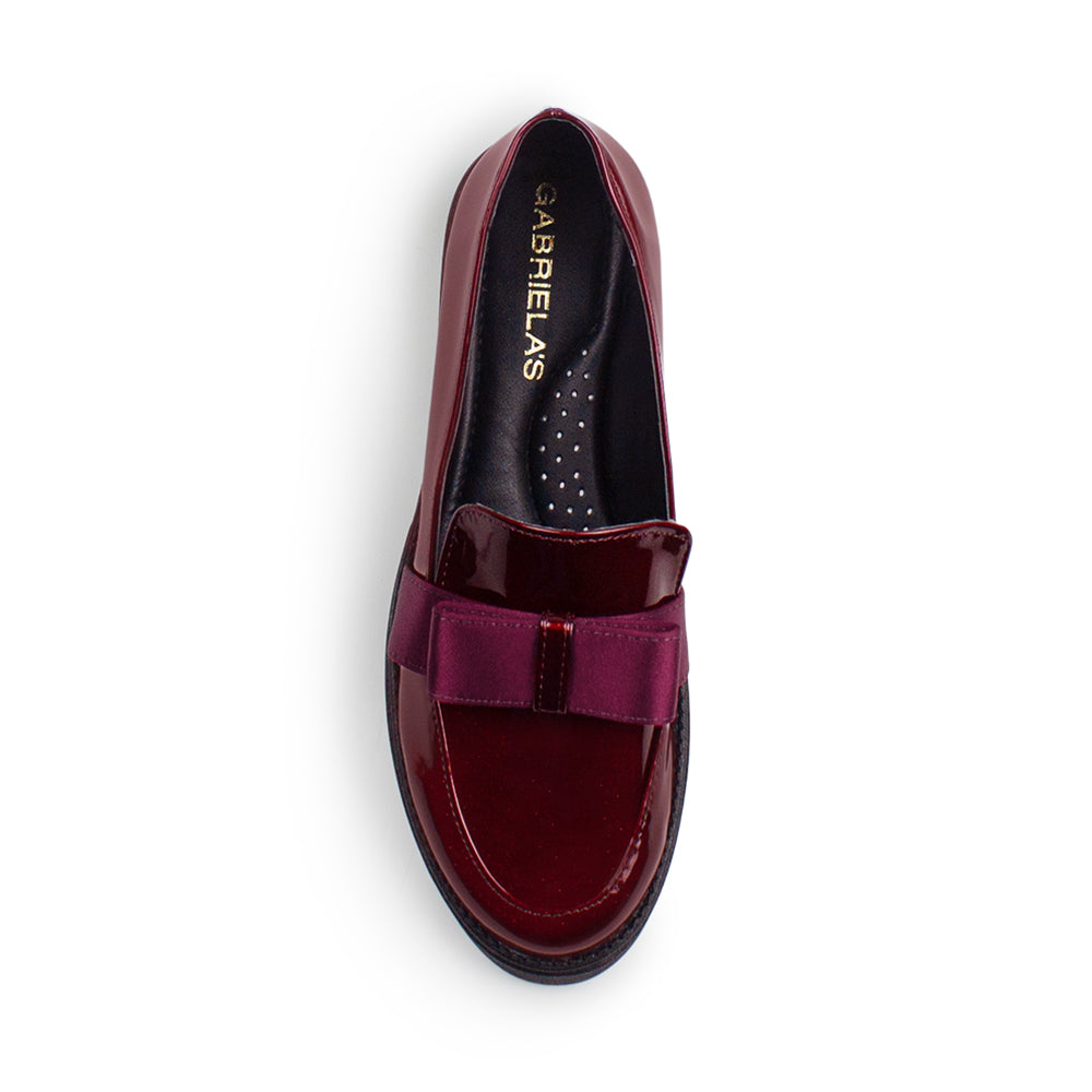 Vista superior del mocasín vino de charol con punta redonda y moño decorativo para dama 