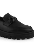 Detalle del material cabra sintético en el mocasín negro para dama con herraje decorativo y suela chunky tipo track 