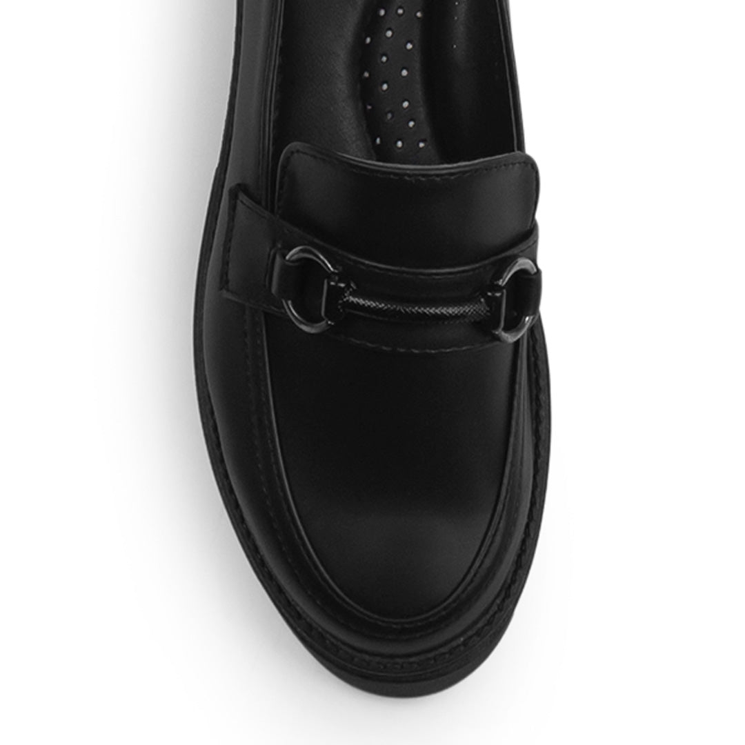 Vista del detalle en el herraje metálico decorativo del mocasín negro para dama con punta redonda y tacón bajo 4cm 