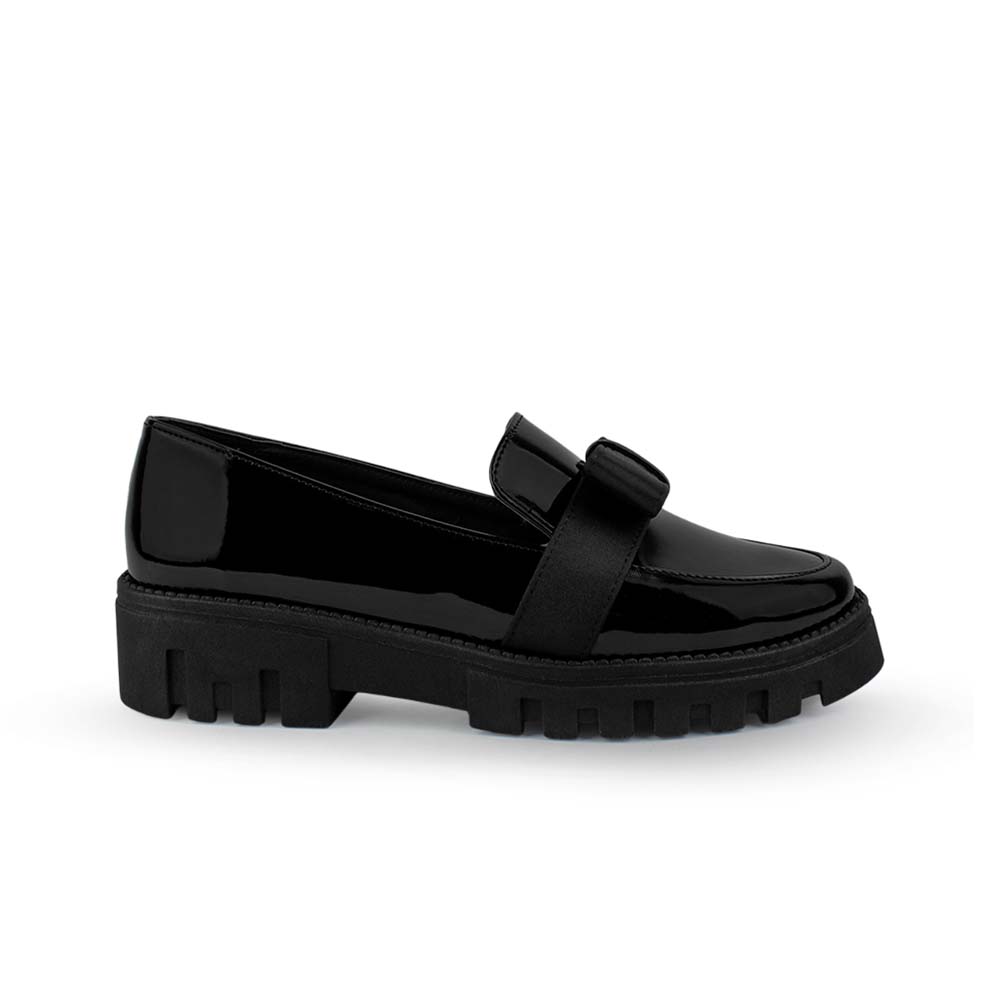 Vista lateral del mocasín negro de charol para dama con plataforma chunky tipo track y moño decorativo. 