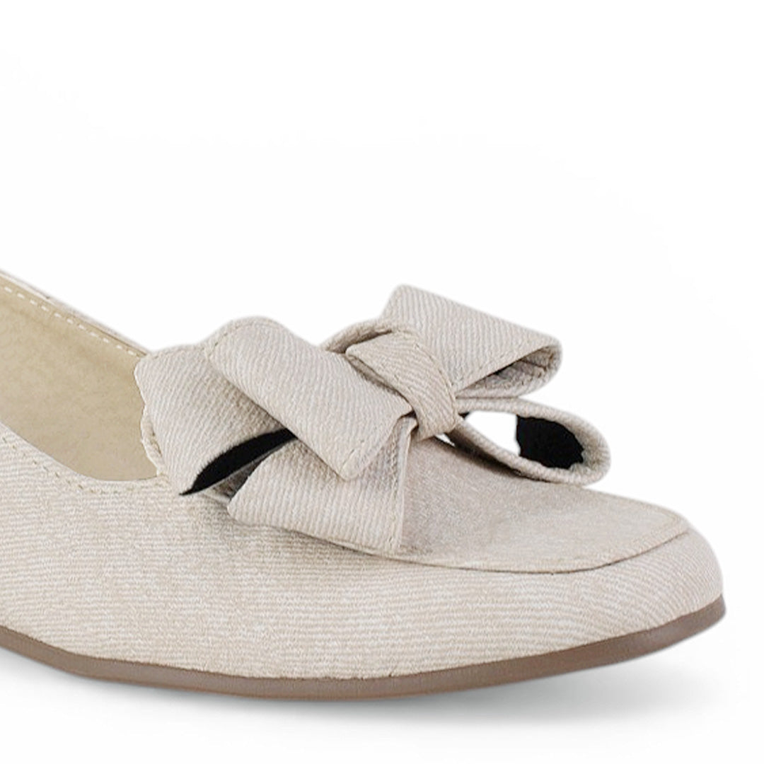 Detalle del material sintético en flat beige con pulsera ajustable de piso y moño en el empeine para dama