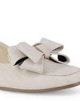 Detalle del material sintético en flat beige con pulsera ajustable de piso y moño en el empeine para dama