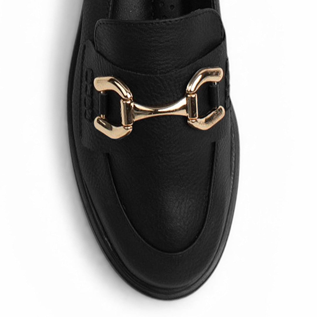 Vista de material sintético en mocasín negro de meter para mujer con tacón bajo de 3cm y herraje decorativo