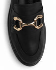 Vista de material sintético en mocasín negro de meter para mujer con tacón bajo de 3cm y herraje decorativo