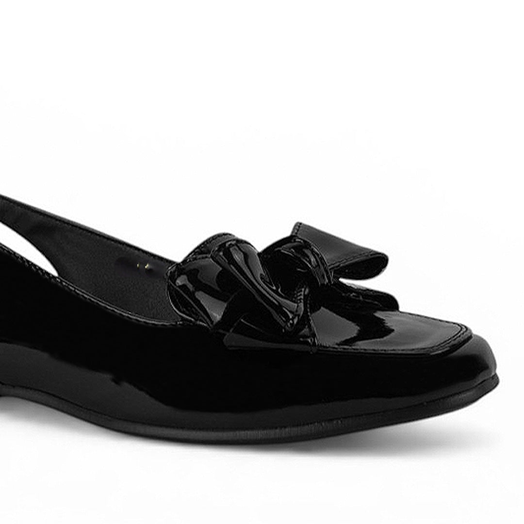 Detalle del material charol en flat negro con pulsera ajustable de piso y moño en el empeine para dama