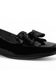 Detalle del material charol en flat negro con pulsera ajustable de piso y moño en el empeine para dama