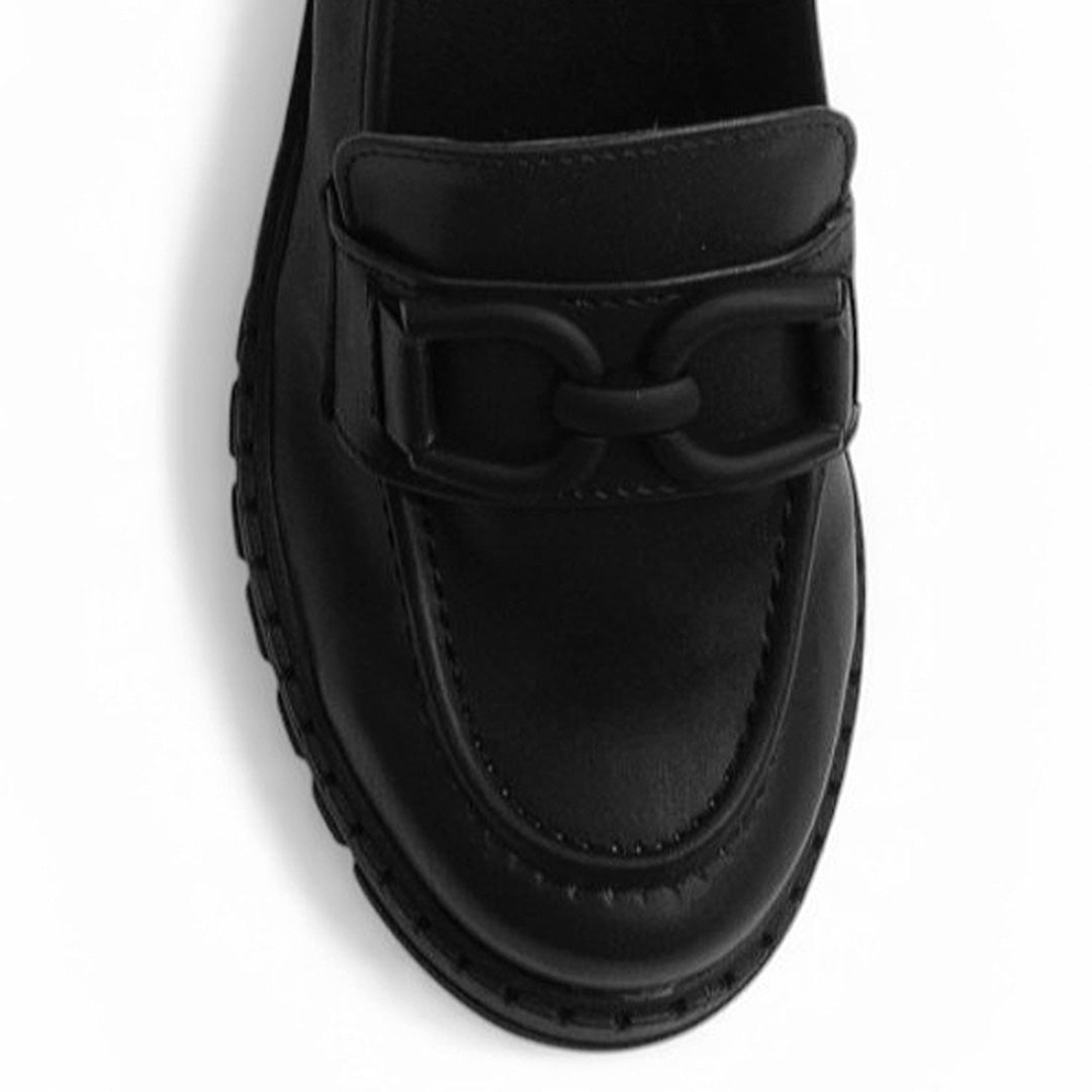 Vista del detalle en herraje decorativo del mocasín negro para dama con punta redonda y plataforma chunky tipo track
