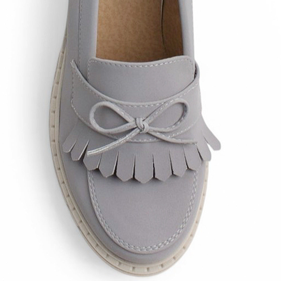 Vista del detalle en moño y flecos del mocasín gris para dama con tacón medio 8 cm 